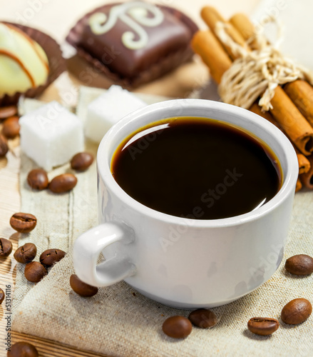 Coffee cup, beans, candy, cinnamon, sugar and anise on a table