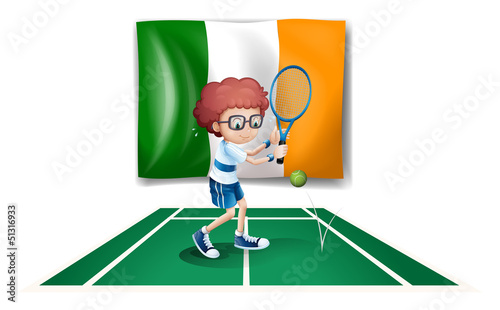 A boy playing tennis in front of the Ireland flag
