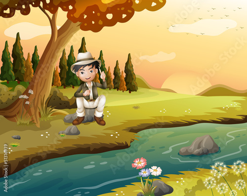 A boy sitting near the riverbank