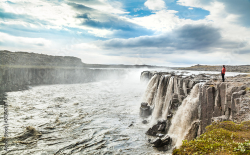 Woman standing near famous Dettifoss waterfall in Iceland photo
