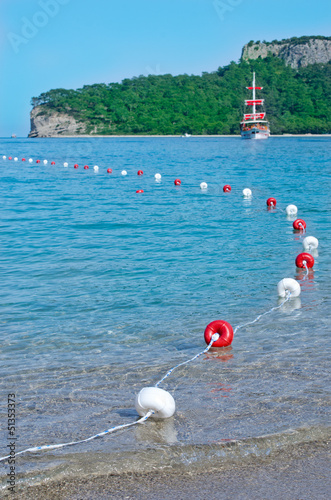 Obraz na płótnie Red and white buoys and a ship with red sails. Kemer, Antalya w salonie
