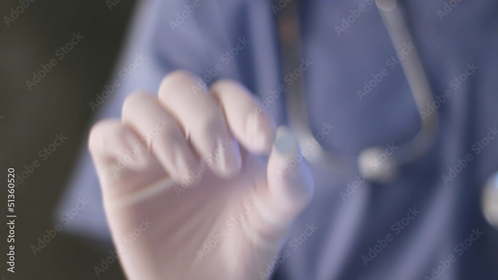 A doctor holds up a pill. A doctor holds up a pill.