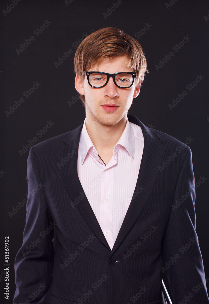 Serious young guy in a suit and stylish glasses
