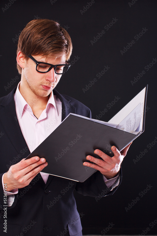 Young guy is reading documents from his folder Young guy is reading documents from his folder