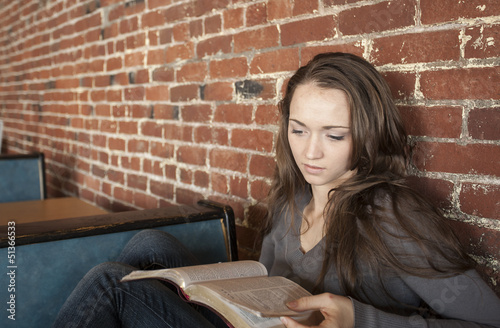 Young Woman with White Coffee Cup Reads Her Bible