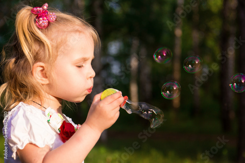 Beautiful little girl blowing soap bubbles