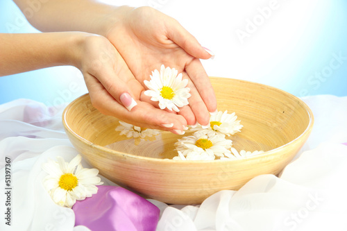 woman hands with wooden bowl of water with flowers,