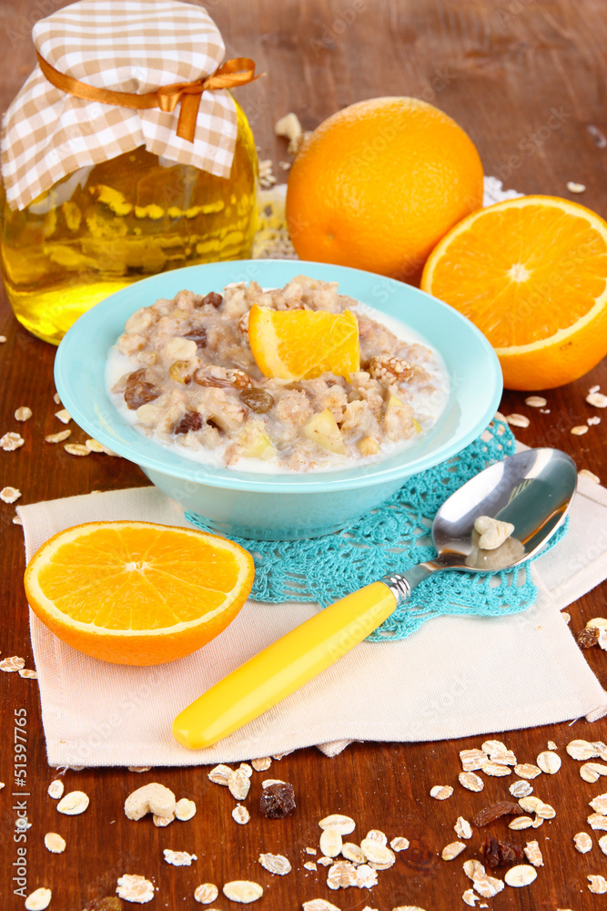 Useful oatmeal in bowl with fruit on wooden table close-up Useful oatmeal in bowl with fruit on wooden table close-up