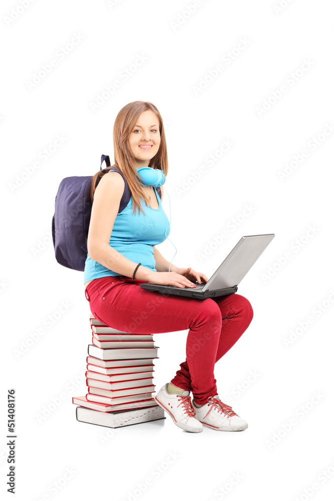 A smiling student with backpack working on a laptop and sitting A smiling student with backpack working on a laptop and sitting