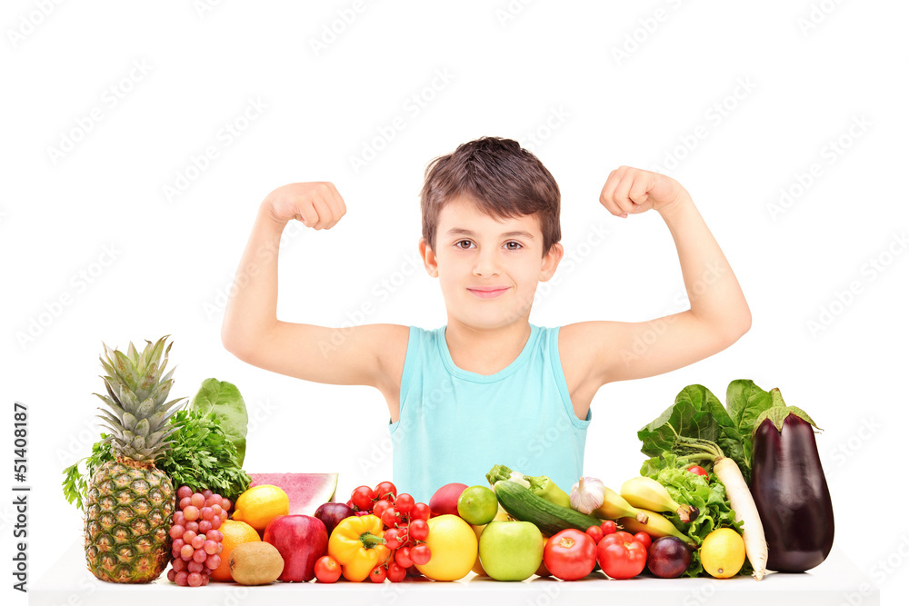Healthy child showing his muscles and sitting on a table full of Healthy child showing his muscles and sitting on a table full of