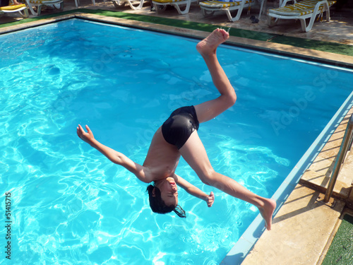 Young boy jumping into pool