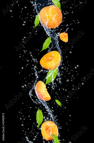 Apricots in water splash, isolated on black background