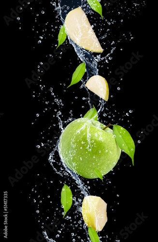 Green apples in water splash, isolated on black background
