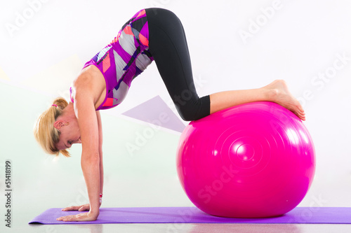 beautiful pilates instructor with pink ball and purple yoga mat