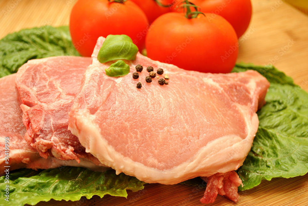A Raw Pork Chop with Fresh Ingredients