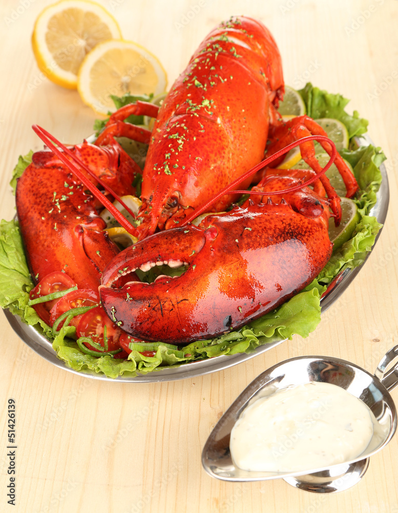Red lobster on platter with vegetables on wooden table close-up Red lobster on platter with vegetables on wooden table close-up