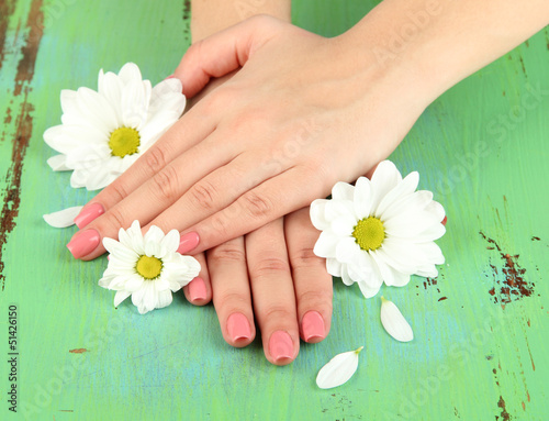 Woman hands with pink manicure and flowers  on color background