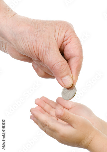 hand of the old person puts a coin in a palm of the child