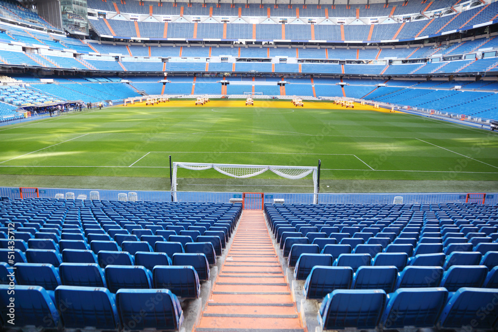 Naklejka premium Pusty stadion piłkarski z niebieskimi siedzeniami, walcowane bramy