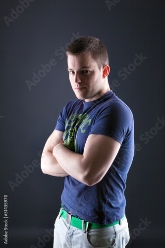 Handsome man looking at camera with arms crossed in a rough post