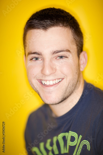 Handsome man smiling at camera with yellow background