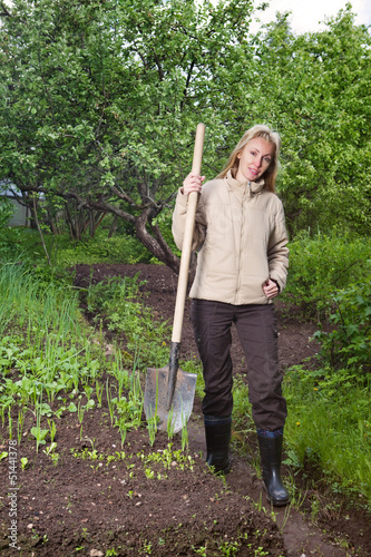 The young woman digs up a garden-bed with the first sprouts 