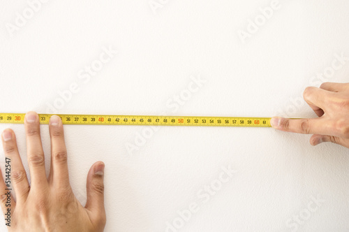 Closeup of a measuring tape in wall white