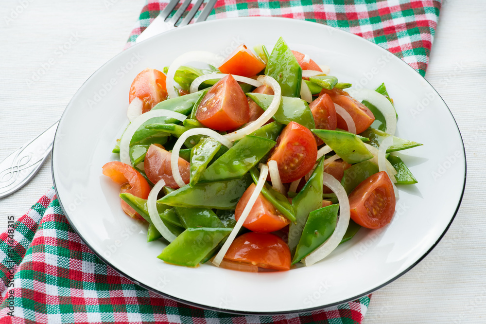 Fresh snow peas and tomato salad on plate Fresh snow peas and tomato salad on plate