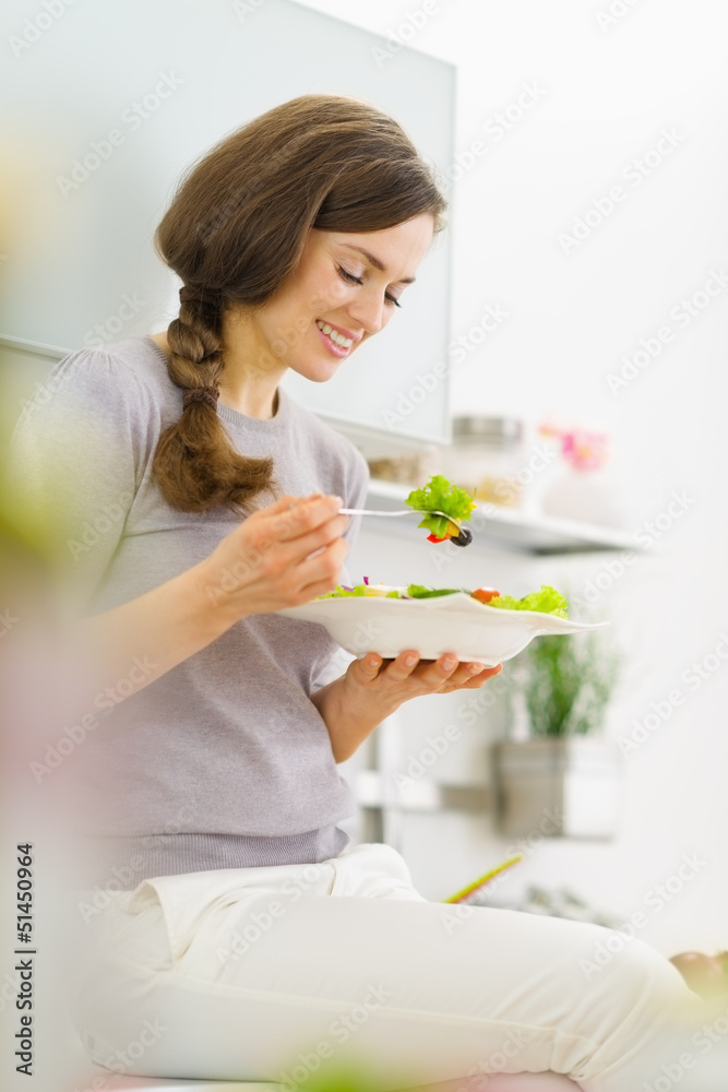 Smiling young woman eating salad and talking mobile phone Smiling young woman eating salad and talking mobile phone