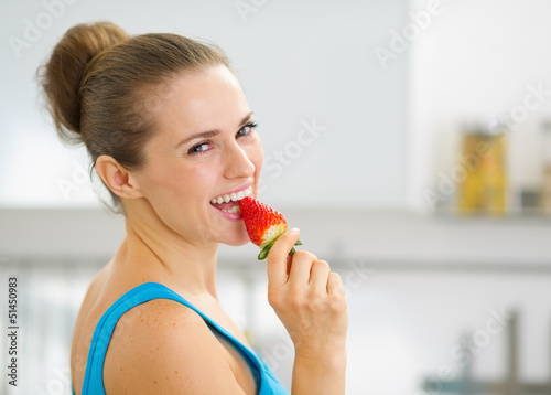 Portrait of happy young woman eating strawberry