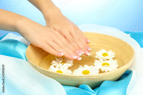 woman hands with wooden bowl of water with flowers,