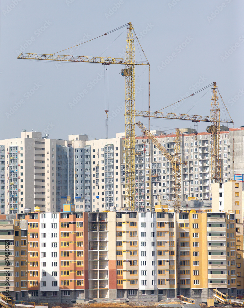 Yellow hoisting tower cranes construction city buildings