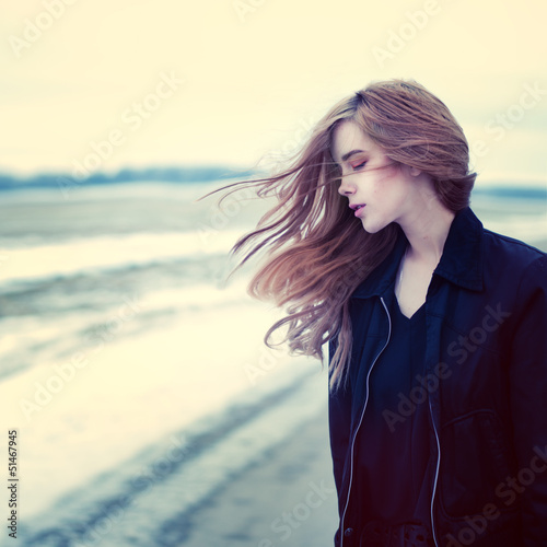 beautiful girl in windy conditions on the road in a field