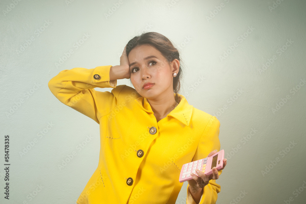 Pretty young Asian woman in yellow suit use calculator. Pretty young Asian woman in yellow suit use calculator.