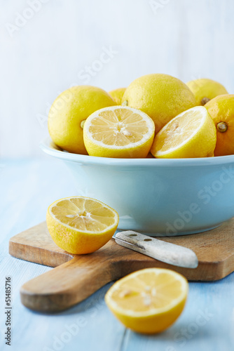 Fresh lemons in a bowl; whole and halved