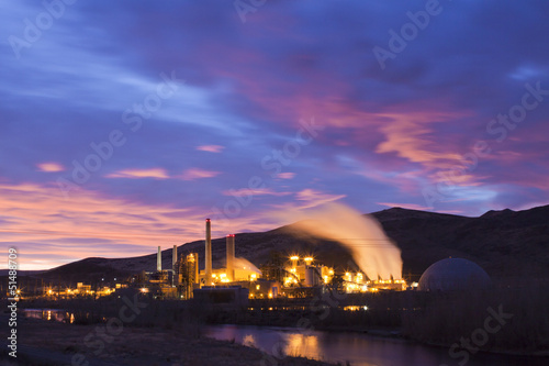 Power plant at sunrise with smoke stacks and steam