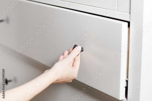 Close up of hand opening a white drawer
