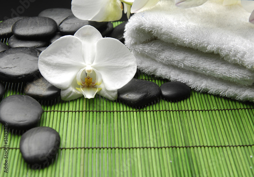 White orchid and stones with white towel on green mat