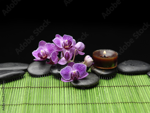 Branch orchid with black stones and candle on mat