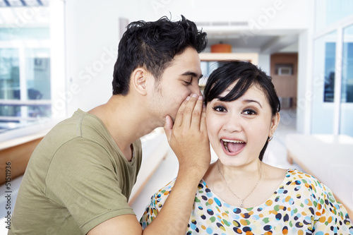 Boyfriend tell secret to girlfriend at home © Creativa Images