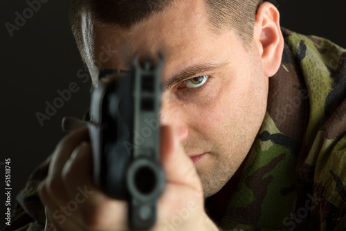 Portrait of man aiming with rifle AK 47 against black background