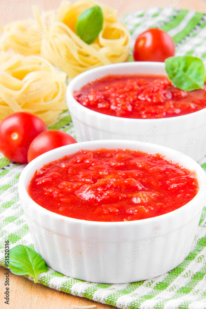 Italian tomato sauce in a white cup with raw pasta, basil and ch Italian tomato sauce in a white cup with raw pasta, basil and ch