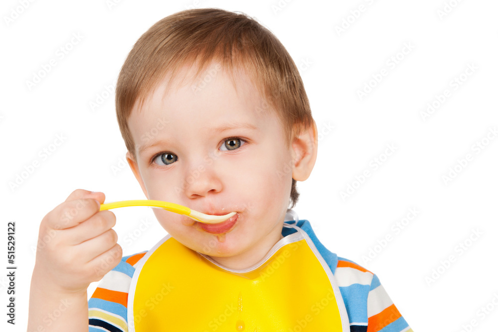 Boy eats with a spoon puree, isolated on white Boy eats with a spoon puree, isolated on white