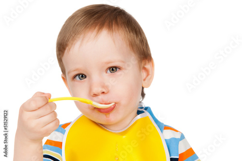 Boy eats with a spoon puree, isolated on white