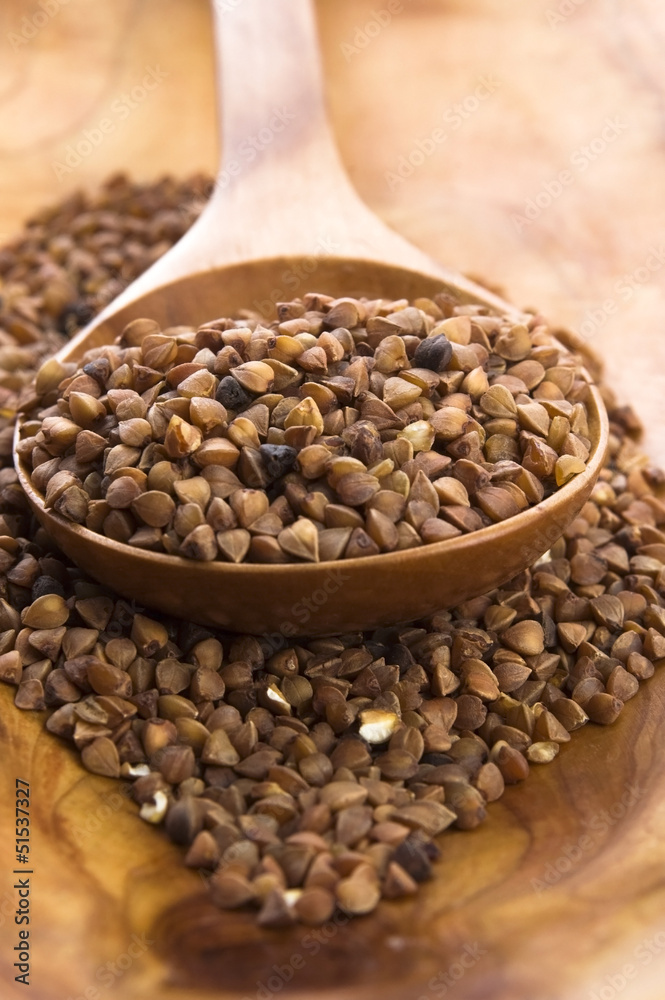 Buckwheat seeds on wooden spoon in closeup Buckwheat seeds on wooden spoon in closeup