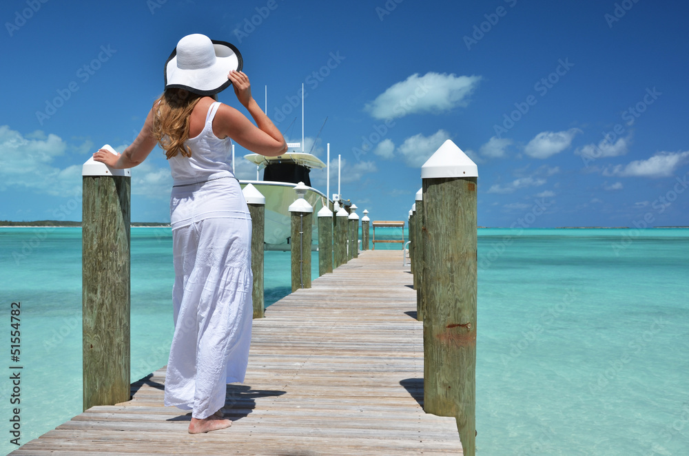 Girl on the wooden jetty looking to the ocean. Exuma, Bahamas