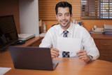 Latin businessman holding a sign while working at his desk