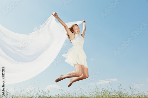 The young beautiful girl in a white dress enjoys a wind, the sun