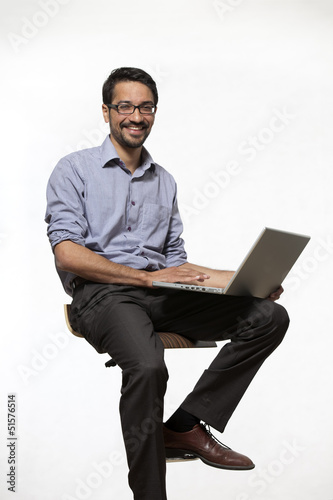 Young Asian Indian sitting on hocker with notebook smiling