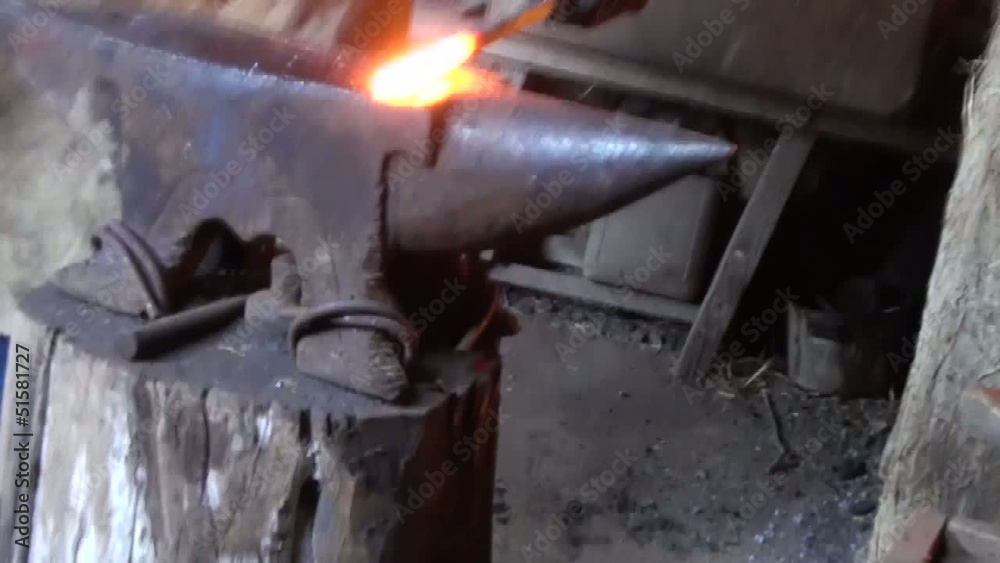 Blacksmith is hammering red-hot piece of iron Blacksmith is hammering red-hot piece of iron